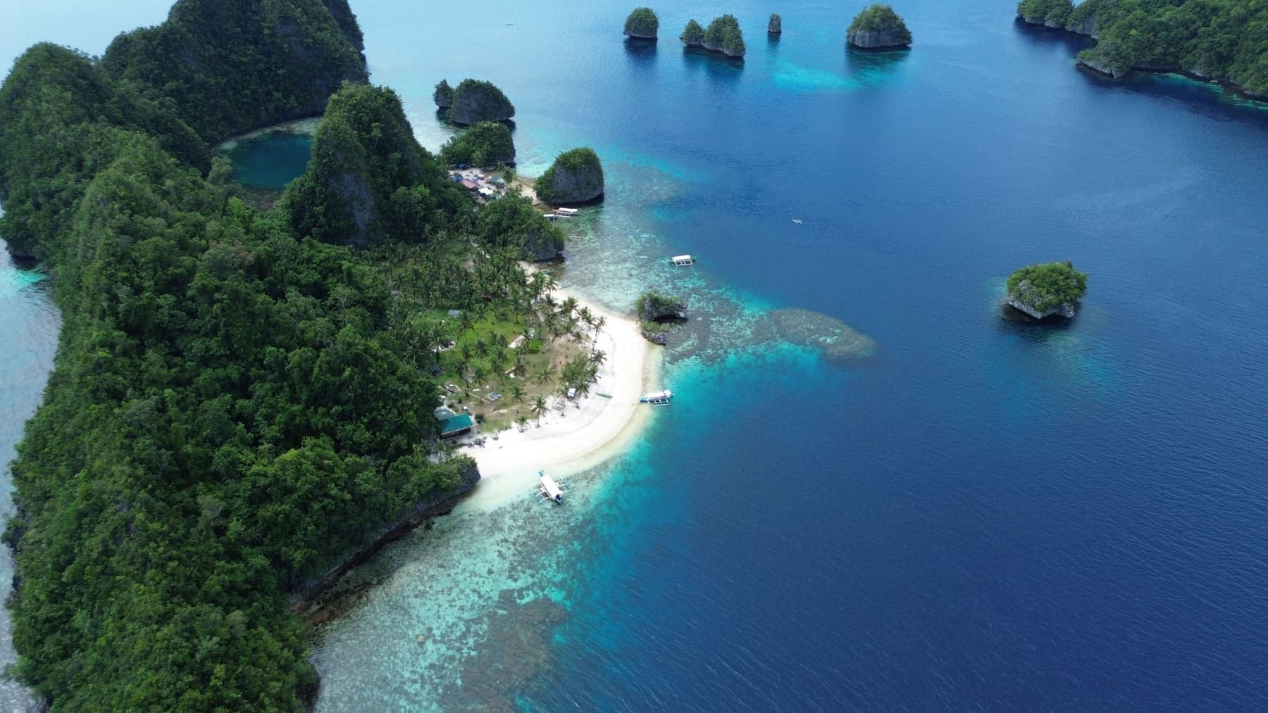 A white sand beach at Pangabangan among limestone islets, with boats drawn up on the shore
