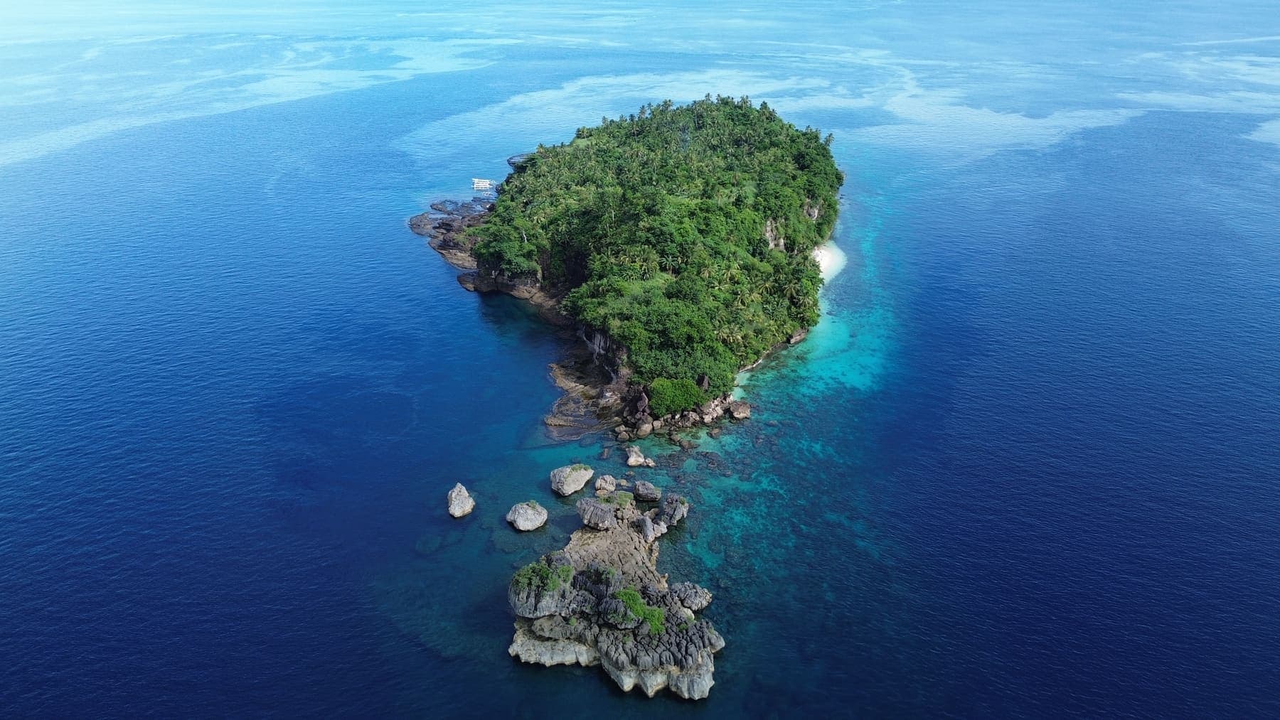 The Hagakhak rock formations rising from the sea, topped with dense green vegetation