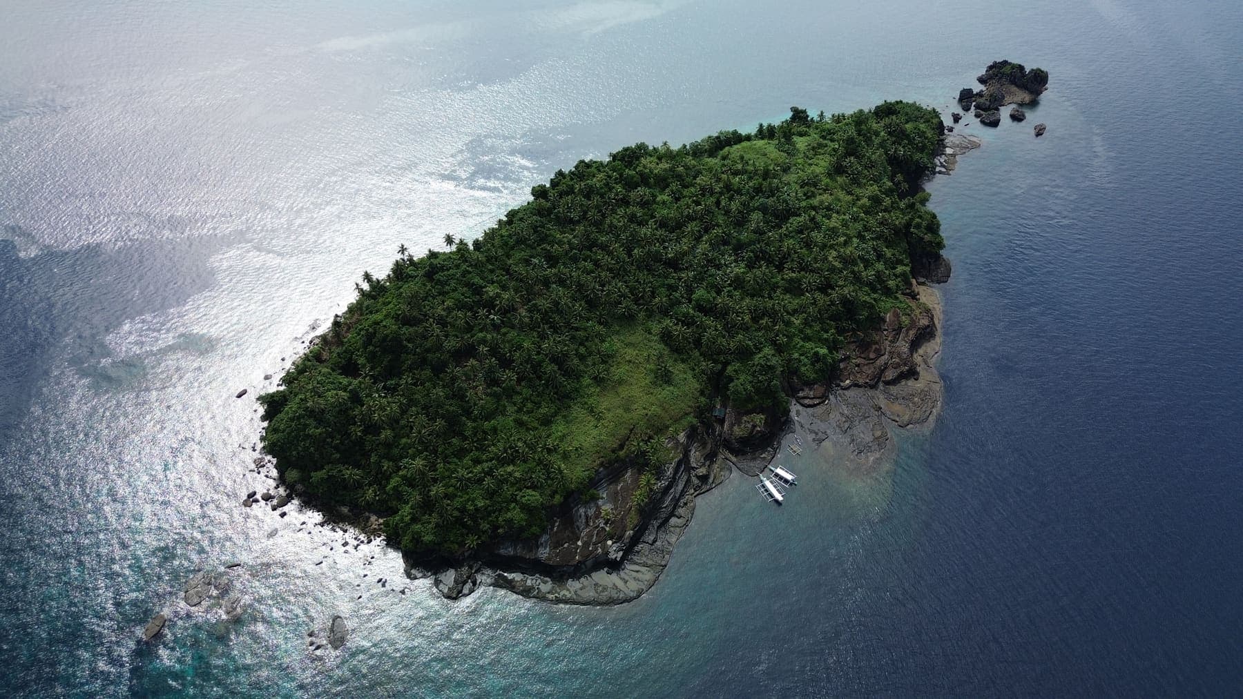 A small forested islet off Libjo under a silver sea, seen from the air